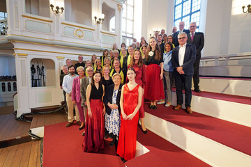Festliches Gruppenfoto im Kirchensaal mit Musizierenden, Organisationsteam und geladenen Gästen beim 10. Herzbrücke-Benefizkonzert im Hamburger „Michel“ der Albertinen-Stiftung.