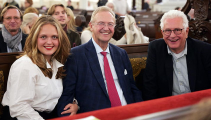 Drei Konzertgäste sitzen auf einer Kirchenbank und blicken freundlich in die Kamera beim 10. Herzbrücke-Benefizkonzert im Hamburger „Michel“ der Albertinen-Stiftung.