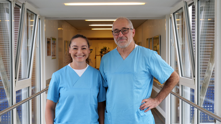 Dr. Anissa Habib-El-Chafchak und Dr. Matthias Gasthaus aus der Klinik für Innere Medizin – Kardiologie im Albertinen Herz- und Gefäßzentrum am Standort Evangelisches Amalie Sieveking Krankenhaus in Hamburg blicken in blauer Funktionskleidung in die Kamera. Dr. Anissa Habib-El-Chafchak und Dr. Matthias Gasthaus aus der Klinik für Innere Medizin – Kardiologie im Albertinen Herz- und Gefäßzentrum am Standort Evangelisches Amalie Sieveking Krankenhaus in Hamburg blicken in blauer Funktionskleidung in die Kamera.