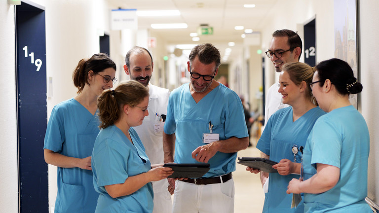 Ein Team aus Pflegekräften und Ärzten in Funktionskleidung im Gespräch mit dem Chefarzt der Herzchirurgie Prof. Dr. Hanke auf einem Stationsflur während einer Visite im Albertinen Herz- und Gefäßzentrum in Hamburg Ein Team aus Pflegekräften und Ärzten in Funktionskleidung im Gespräch mit dem Chefarzt der Herzchirurgie Prof. Dr. Hanke auf einem Stationsflur während einer Visite im Albertinen Herz- und Gefäßzentrum in Hamburg