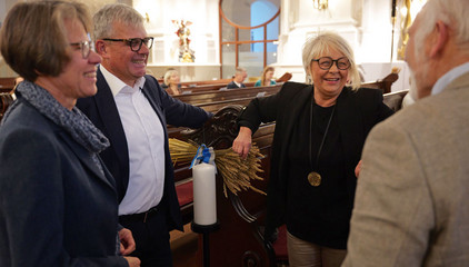 Vier geladene Gäste unterhalten sich im Kirchensaal neben den Kirchenbänken beim 10. Herzbrücke-Benefizkonzert im Hamburger „Michel“ der Albertinen-Stiftung.