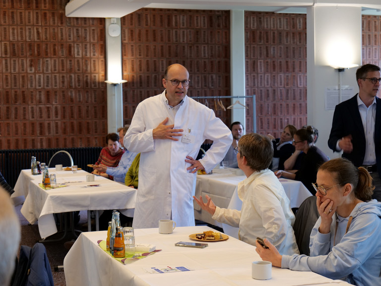 Prof. Dr. med. Ernst von Dobschütz, Chefarzt Zentrum für Endokrine Chirurgie und Ärztlicher Direktor, steht im Vortragsraum und unterhält sich mit einer Kollegin bei der Fachveranstaltung 11. Amalie Tag der Hausärztinnen und Hausärzte im Evangelischen Amalie Sieveking Krankenhaus in Hamburg-Volksdorf.