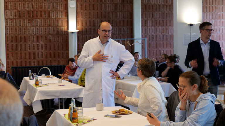 Prof. Dr. med. Ernst von Dobschütz, Chefarzt Zentrum für Endokrine Chirurgie und Ärztlicher Direktor, steht im Vortragsraum und unterhält sich mit einer Kollegin bei der Fachveranstaltung 11. Amalie Tag der Hausärztinnen und Hausärzte im Evangelischen Amalie Sieveking Krankenhaus in Hamburg-Volksdorf.
