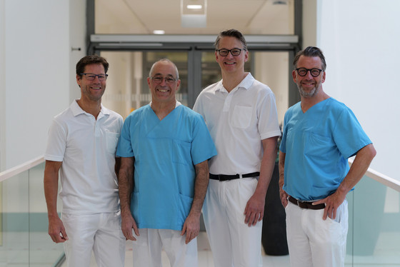 Die Chefärzte Dr. Lars Kock, Dr. Matthias Gasthaus, Prof. Dr. Karsten Sydow und Prof. Dr. Thorsten Hanke des Albertinen Herz- und Gefäßzentrums in Hamburg stehen nebeneinander und blicken lächelnd in die Kamera
